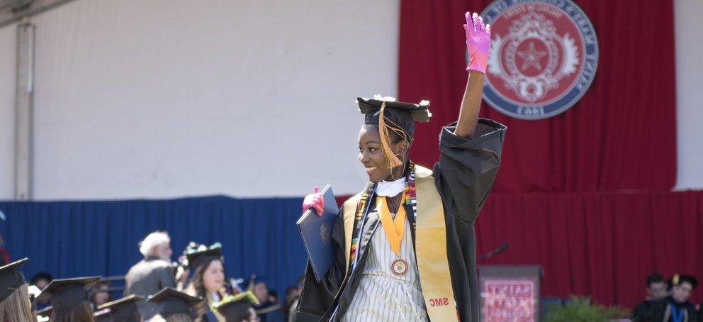 student graduating wearing pink glove and a smile